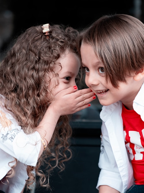 petite fille chuchotant à oreille garçon